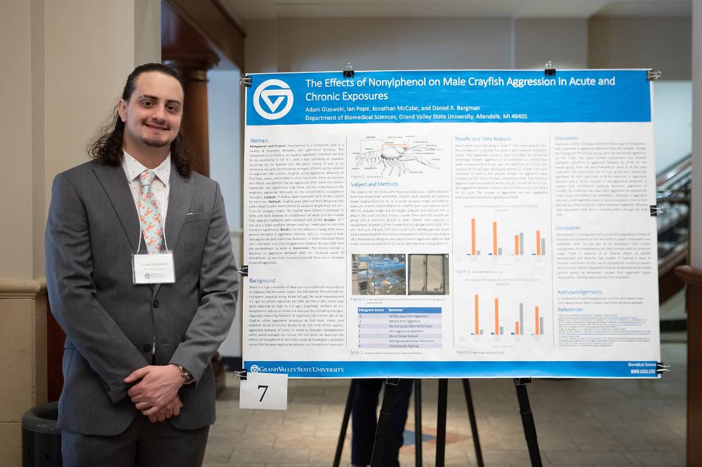 Biomedical sciences graduate student, Adam Gizowski, standing in front of his poster.